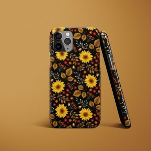 May include: A black phone case with a floral pattern featuring sunflowers, leaves, and berries. The case has a cutout for the camera lens.