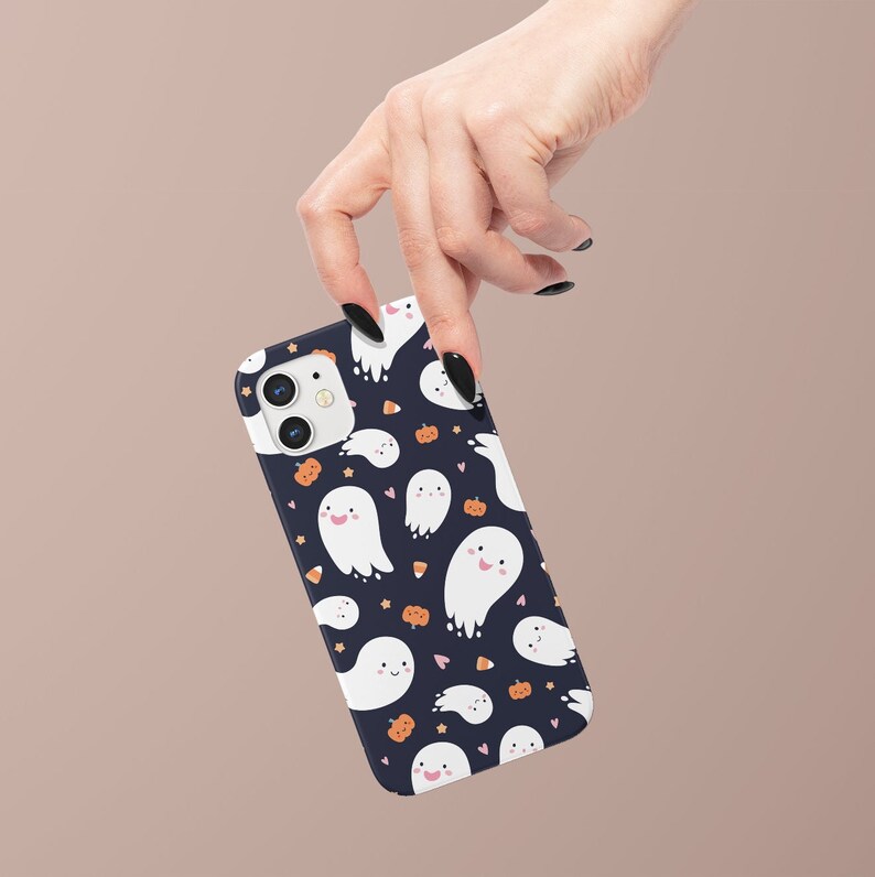 May include: A black phone case with a white ghost and pumpkin pattern. The case has a white background with orange and pink accents.