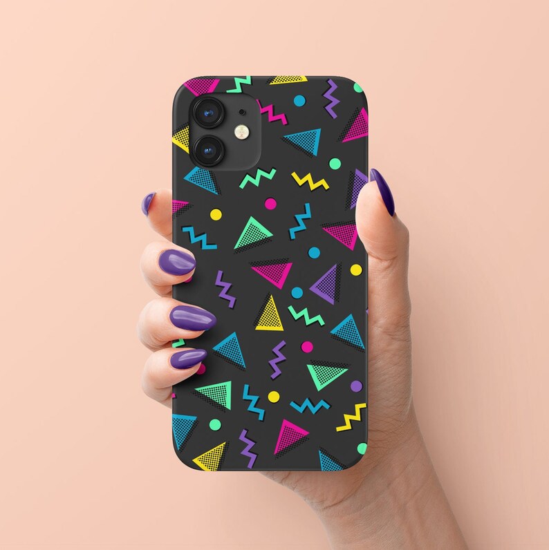 May include: Black phone case with a colorful geometric pattern of triangles, zigzags, and dots in neon colors. The case is held in a hand with purple nail polish.