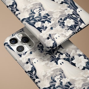 May include: Two white iPhone cases with a dark blue background featuring a repeating pattern of white ghosts and flowers.