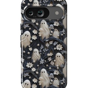 May include: A black phone case with a white ghost pattern on a dark blue background. The ghosts are surrounded by white flowers and vines.