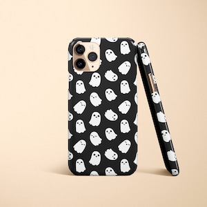 May include: Black phone case with a white ghost pattern. The case has a camera cutout and a black border.
