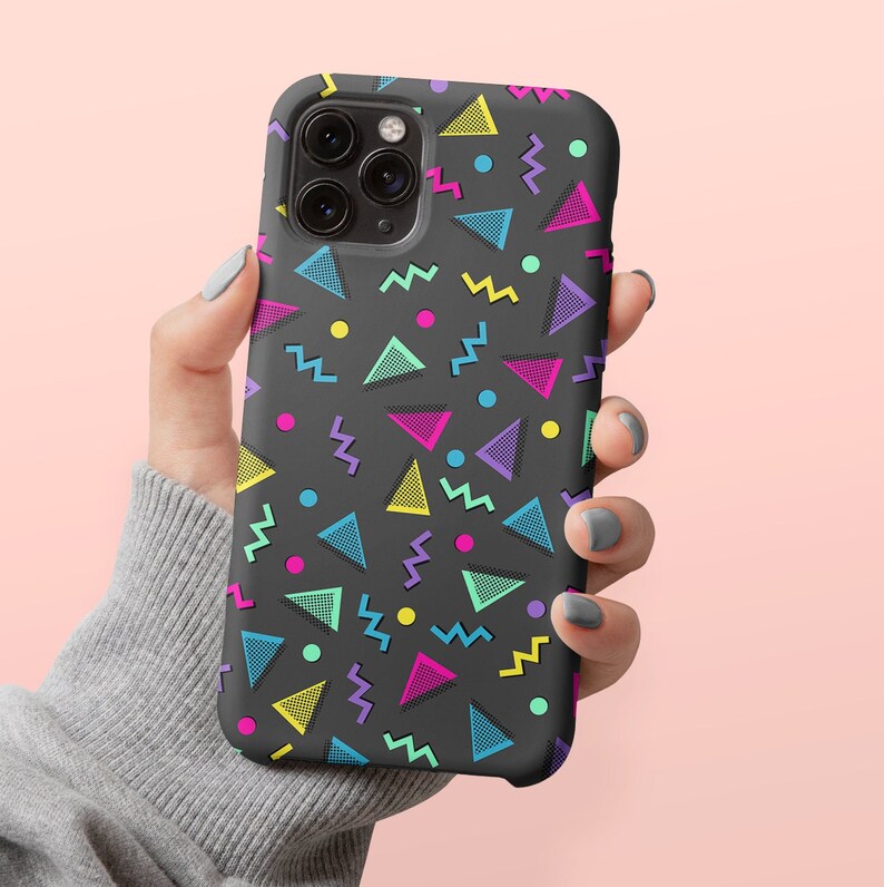 May include: A black phone case with a vibrant 80s-inspired geometric pattern. The design features colorful triangles, zigzags, and circles in shades of pink, yellow, blue, and purple. The case is designed to fit a smartphone.