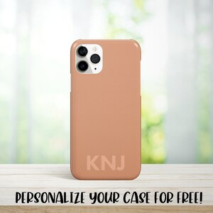 May include: A peach-colored phone case with a white camera bump and the initials "KNJ" printed on the back.  Personalize your case for free!