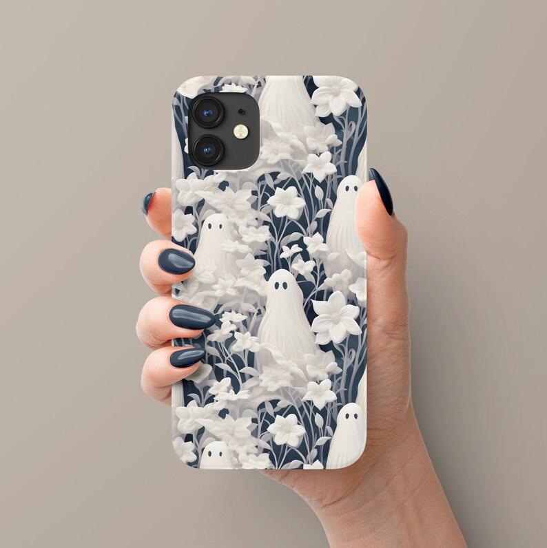 May include: A white iPhone case with a dark blue background featuring a repeating pattern of white ghosts and flowers.