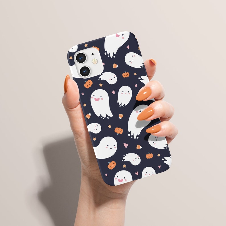 May include: A black phone case with a pattern of white ghosts, orange pumpkins, and candy corn on a dark blue background.