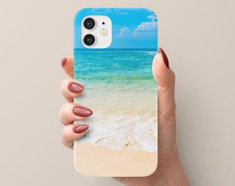 May include: A white iPhone case with a blue sky and ocean beach scene. The case has a camera cutout and a white border.