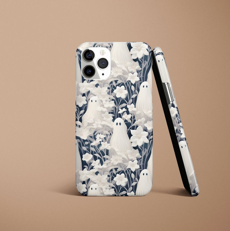 May include: A white iPhone case with a pattern of white ghosts and flowers on a dark blue background.