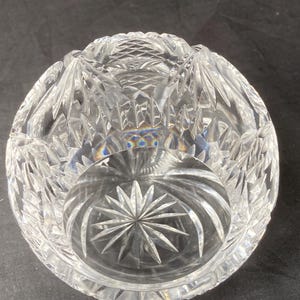 Puede incluir: Un cuenco de vidrio transparente con un diseño de cristal tallado. El cuenco tiene un patrón de estrella en el centro y un patrón geométrico alrededor del borde.