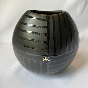 Könnte beinhalten: Eine schwarze und graue Poole-Keramikvase mit runder Form und glänzendem Finish. Die Vase hat horizontale und vertikale Streifenmuster. Ein Poole Pottery-Aufkleber ist sichtbar.