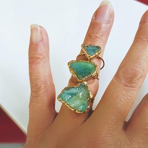A set of 3 raw Peruvian Opal rings set in 18k Gold worn by a woman