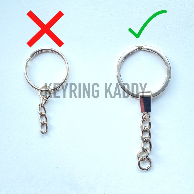 May include: Two silver keychains with a circular ring and a chain. The keychain on the left has a shorter chain, while the keychain on the right has a longer chain. The keychain on the left is marked with a red X, while the keychain on the right is marked with a green checkmark. The text "KEYRING KADDY" is visible in the image.