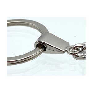 May include: Silver key chain with a round ring and a metal clasp. The clasp is attached to a silver chain.