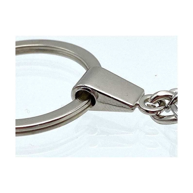 May include: Silver key chain with a round ring and a metal clasp. The clasp is attached to a silver chain.