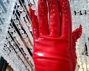 May include: Red leather gloves with a shiny finish and red rhinestone embellishments on the fingers.