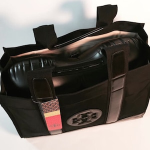 May include: Black tote bag with a black leather trim and a black and silver logo. The bag is open and has a black and white patterned tag attached to it.