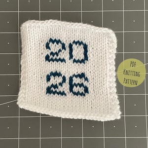 May include: A square white knitted swatch featuring the dark blue numbers 20 and 26 centered in a stacked arrangement. To the right, a circular light green graphic contains the black text PDF KNITTING PATTERN, indicating the item's format.