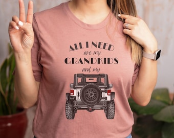 Puede incluir: Una camiseta rosa con el texto "All I need are my grandkids and my" sobre un Jeep blanco con neumáticos negros. El texto "Pick your truck color" está en la parte inferior de la imagen.