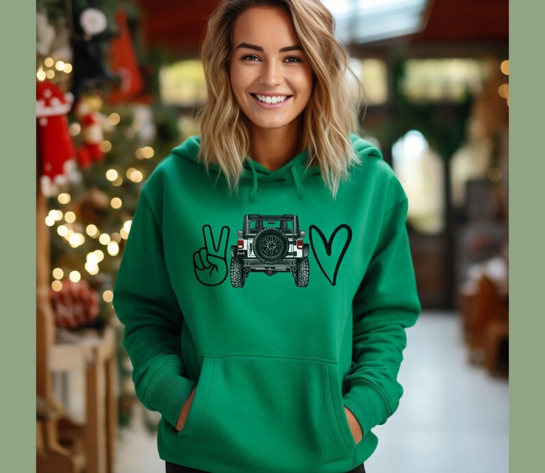 May include: A bright green hooded sweatshirt featuring a graphic print on the chest. The design consists of a black peace sign, a detailed illustration of the rear view of a white off-road vehicle with a spare tire, and a black heart symbol.