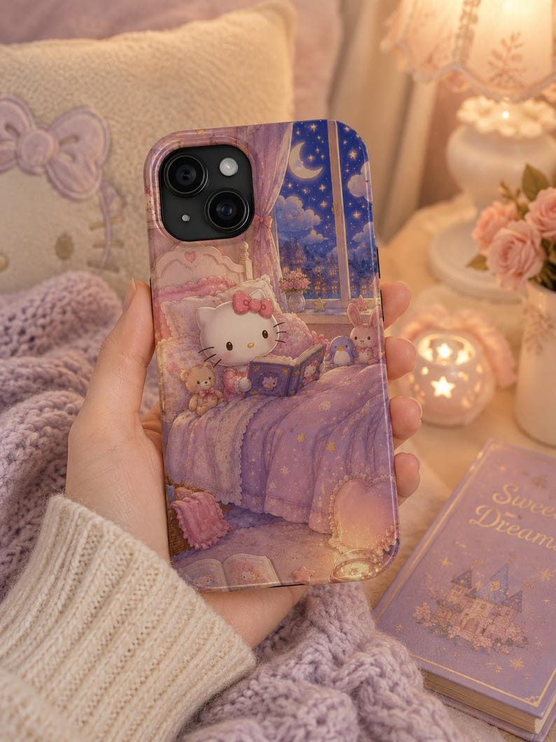 May include: A smartphone case featuring a printed illustration of a white cat character sitting in a bed reading a book. The scene includes a night sky with a crescent moon visible through a window, purple bedding, and small plush toys.