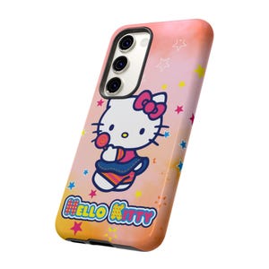 May include: A phone case with a Hello Kitty design, holding a lollipop, set against a pink, orange, and yellow gradient. The case has a white camera module and the words "Hello Kitty" in a colourful font.