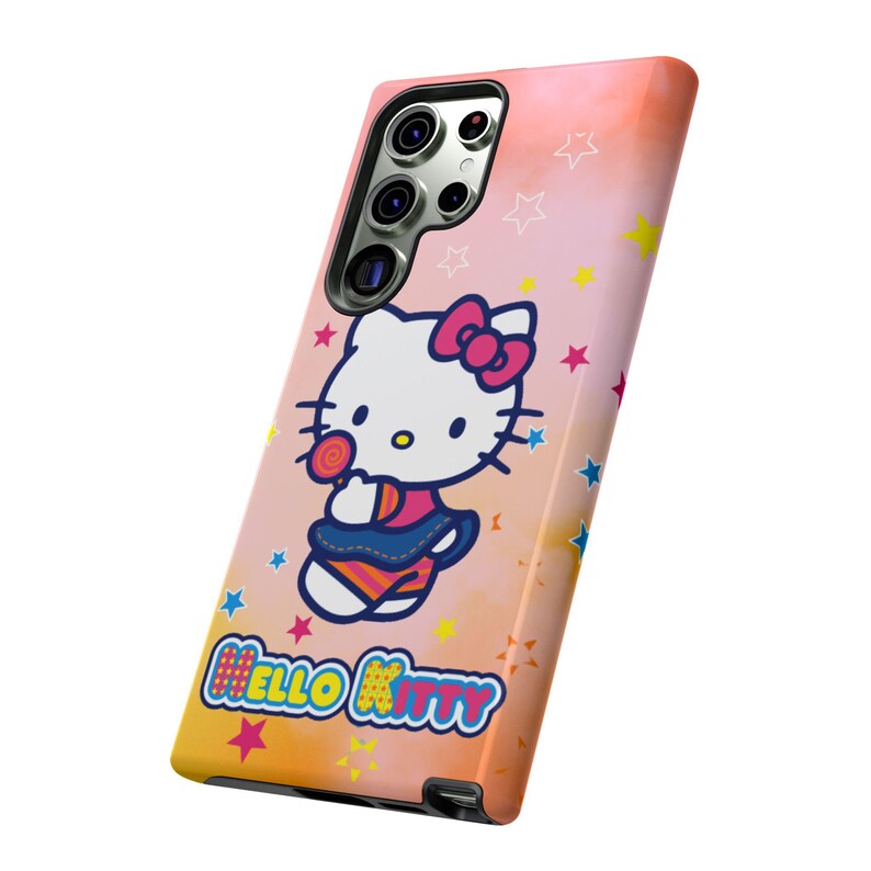 May include: A phone case with a Hello Kitty design. The case has a pink, orange, and yellow gradient background with star accents. Hello Kitty is holding a lollipop. The words "Hello Kitty" are printed at the bottom.