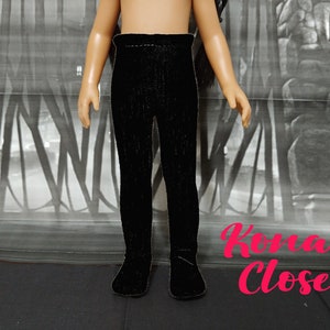 May include: Black leggings for a doll. The leggings are made of a soft, stretchy fabric and have a ribbed texture.