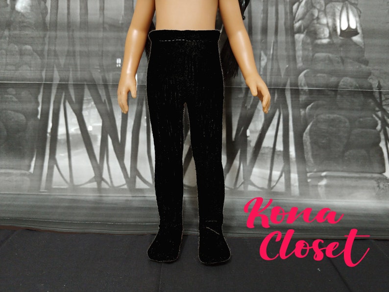 May include: Black leggings for a doll. The leggings are made of a soft, stretchy fabric and have a ribbed texture.