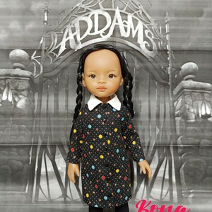 May include: A black and white doll with long black braids wearing a black dress with colorful polka dots and black tights. The doll is standing in front of a black and white backdrop with the word "Addams" written in a gothic font.