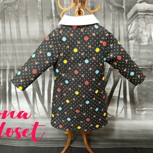 May include: A black coat with a white collar and a colorful polka dot pattern. The dots are red, yellow, and blue.