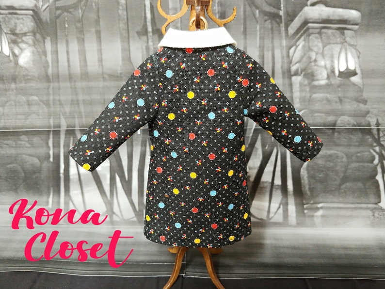 May include: A black coat with a white collar and a colorful polka dot pattern. The dots are red, yellow, and blue.