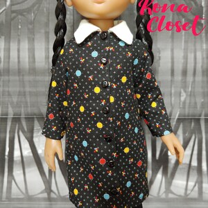 May include: A black and white polka dot dress with a white collar and button closure. The dress has yellow, red, and blue accents. Kona Closet is written in pink on the background.