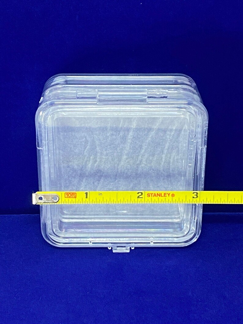 May include: A clear plastic storage box with a hinged lid. The box is approximately 5 cm wide.