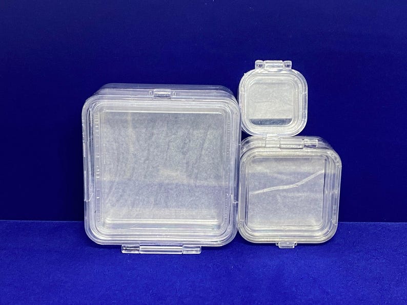 May include: Three clear plastic square boxes with lids, nested inside each other. The boxes are empty.