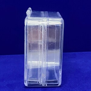 May include: A clear plastic storage box with a hinged lid. The box is empty and has a rectangular shape.