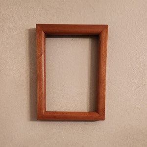 May include: A simple, rectangular wooden picture frame with a natural wood finish.