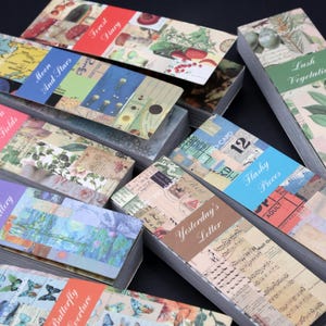 May include: A stack of colorful paper pads with various vintage-inspired designs. Each pad features a different title, such as "Flowers in the Fields", "Moon and Stars", "Yesterday's Letter", and "Flashy Pieces".