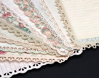 May include: A stack of decorative paper with scalloped edges and floral patterns. The paper is beige and cream with a vintage aesthetic.