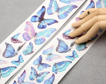 May include: A white ribbon with a repeating pattern of blue and purple butterflies. The ribbon is on a grey surface.
