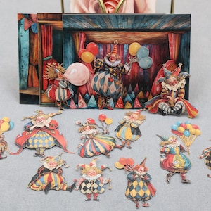 May include: A detailed image of a miniature circus stage with a backdrop and several paper cut-out clowns. The clowns are dressed in colourful costumes, some holding balloons, creating a playful and festive atmosphere.