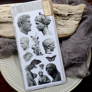 May include: A sheet of vintage-style stickers featuring black and white images of classical sculptures, including busts, figures, and a butterfly. The stickers are perfect for adding a touch of history and elegance to journals, planners, and other craft projects.