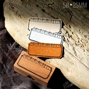 May include: Three blank rectangular stamps with a brown, white and cream paper background. The stamps have a black border and a grid pattern. The stamps are 50 x 25 mm. A wooden stamp with a similar grid pattern is also shown.