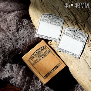 May include: A wooden stamp and two paper labels with the text "AGATHA PRIMROSE" and "Potions & Possels SALEM TOWN". The stamp measures 4.5cm x 4cm. The labels and stamp have a vintage apothecary theme.