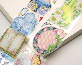 Könnte beinhalten: Ein Blatt dekoratives Washi-Tape mit floralem und kariertem Design. Das Band zeigt ein Buch, eine Blume, einen Schmetterling, einen karierten Kreis und ein kariertes Kleeblatt.
