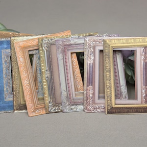 May include: A set of eight ornate picture frames in various shades of gold, brown, and blue. The frames are all different sizes and have intricate details.