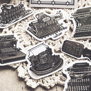 May include: A set of eight vintage typewriter stickers in black and white. The stickers feature different styles of typewriters, including a manual typewriter, an electric typewriter, and a vintage typewriter with a keyboard.
