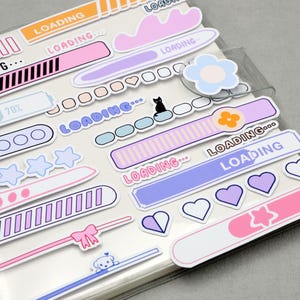 May include: A collection of colorful stickers with a 'loading' theme. Designs include progress bars, clouds, stars, hearts, and a small black cat. The stickers are in pastel colors like pink, blue, and purple.