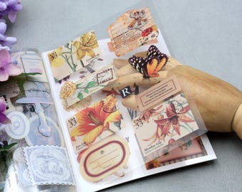 Pode incluir: Uma coleção de autocolantes em estilo vintage com desenhos florais e de borboletas. Os autocolantes incluem imagens de lírios, rosas e selos postais, com uma borboleta em cima. A paleta de cores inclui tons de bege, laranja e amarelo.