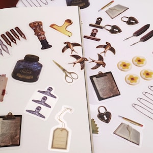 May include: A sheet of stickers featuring various vintage-inspired designs, including a bottle of ink, a quill pen, a bird, a lock, a clipboard, a safety pin, and a tag. The stickers are printed on white paper and have a matte finish.