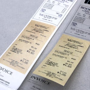 May include: Two vintage-style receipts with the text "Invoice" and "领取证" printed on them. The receipts are on a light gray surface. The text on the receipts is in Japanese and English.